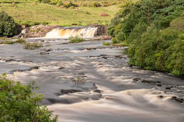 Aasleagh Falls with trees and farm fields