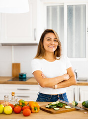 Portrait of pleased housewife preparing salad in modern kitchen