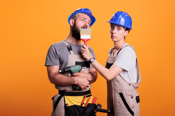 Construction workers yawning and being sleepy in studio, posing with multiple renovating tools. Exhausted repairman and handywoman holding building instruments, being tired and asleep.