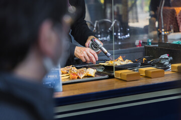 A chef at a street kitchen of the Tsukiji fish market in Tokyo preparing seafood using a Bunsen...