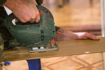 carpenter using an electric jigsaw to create a new piece of furniture from recycled materials. 