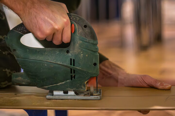 Mastering the Art of Woodwork: A skilled carpenter wields an electric jigsaw, crafting wooden...