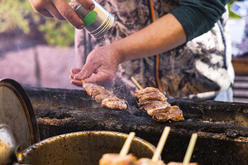 a cook from a street kitchen seasoning skewers of meat in Tokyo, Japan