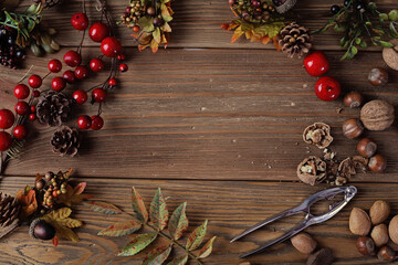 autumn leaves, pine cones and nuts on rustic wooden background