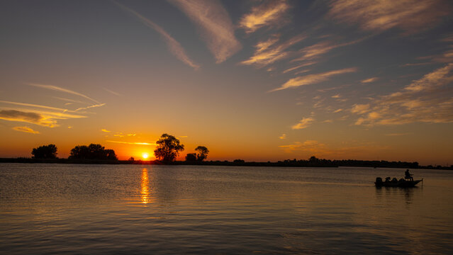 Fishing in boat in silhouette at sunrise on the river