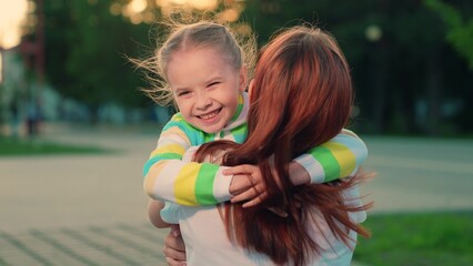 Child, daughter runs to mom hugs her in park on street in autumn. Happy family. Carefree childhood, joyful run of baby to mother. Child smiles cheerfully plays in summer on street with parent. Kid mom