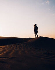 Fototapeta na wymiar Woman walking in desert at sunset
