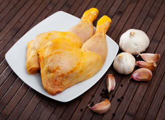 Fresh chicken legs quarters on wooden background with parsley and garlic