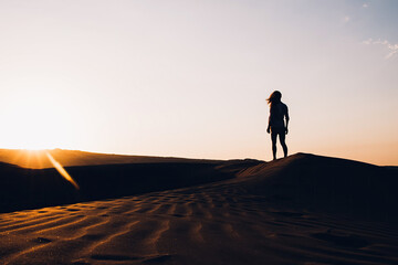 Fototapeta na wymiar Woman walking in desert at sunset