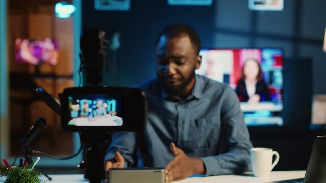 Content creator doing technology review of wireless portable speaker for online platforms channel. African american influencer presenting music playing device to his audience