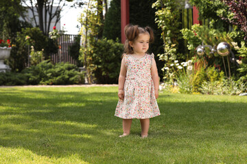 Cute little girl walking on green grass in park