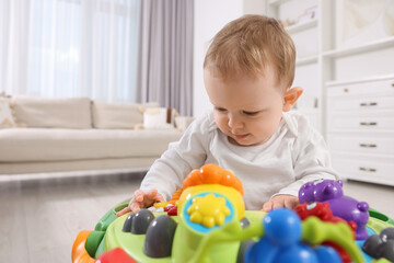 Cute little boy in baby walker at home, space for text