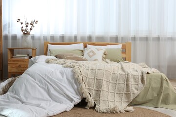 Large comfortable bed with soft pillows, duvet and blanket in room. Home textile