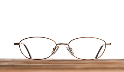 Stylish glasses with metal frame on wooden table against white background