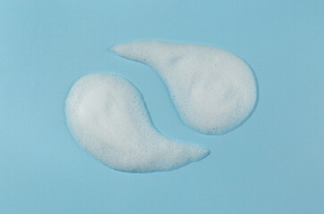 Samples of cleansing foam on light blue background, above view. Cosmetic product