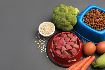 Raw meat in bowl and healthy products for pet on black background, above view. Space for text