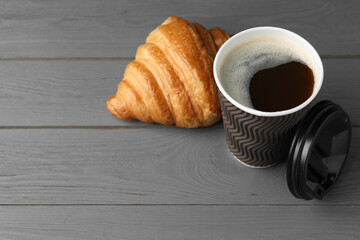 Coffee to go. Paper cup with tasty drink and croissant on grey wooden table. Space for text
