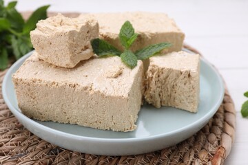 Pieces of tasty halva and mint on table, closeup