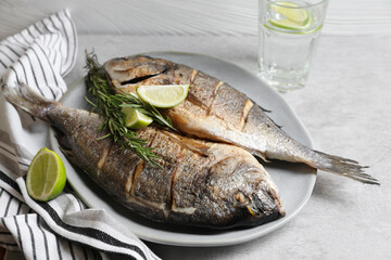 Delicious baked fish with rosemary and lime on grey table, closeup. Seafood