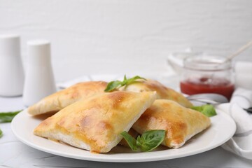 Delicious samosas and basil on white table, closeup