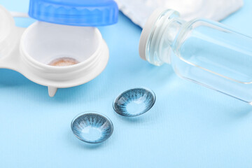 Case with color contact lenses and bottle on light blue background