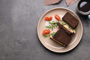 Delicious sandwiches with boiled sausage, tomato, cheese and arugula on grey table, flat lay. Space for text