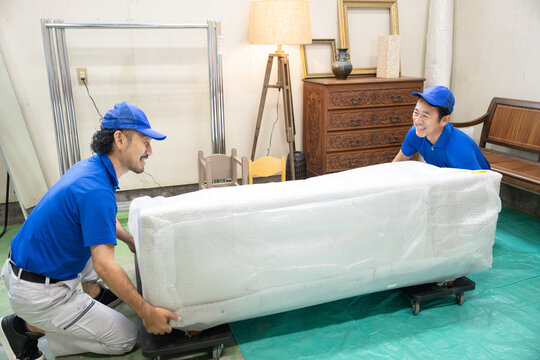 荷物を運ぶ引っ越しや配送業のスタッフ　重い持ち上げる