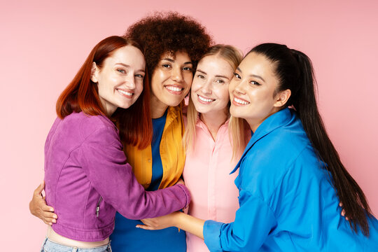 Group beautiful smiling multiracial women wearing stylish colorful clothing looking at camera isolated on background. Portrait happy different fashion models posing for pictures. Diversity concept