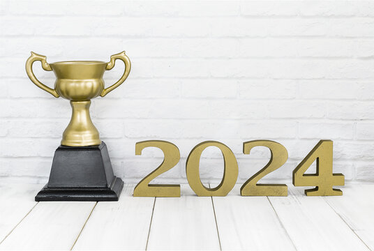 2024 new year and golden trophy on white wood table over white background with copy space , winner or success concept