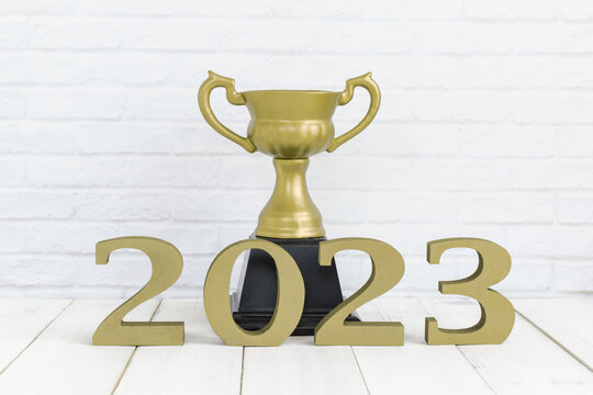 2023 new year and golden trophy on white wood table over white background with copy space , winner or success concept