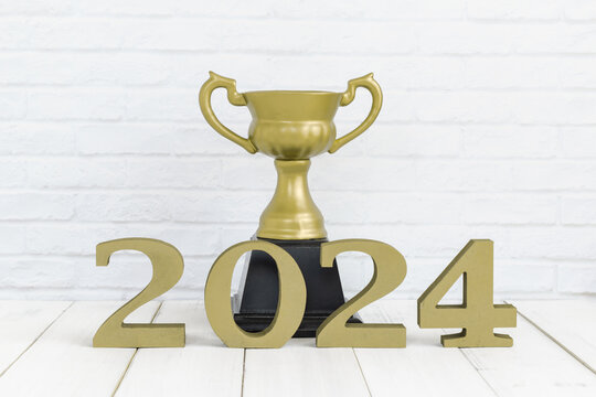 2024 new year and golden trophy on white wood table over white background with copy space , winner or success concept