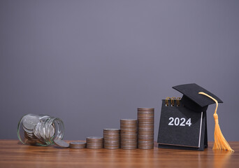 Study goals, 2024 Desk calendar with graduation hat and stack of coins. The concept of saving money for education, student loan, scholarship, tuition fees in New Year 2024 - obrazy, fototapety, plakaty