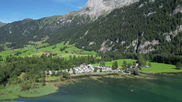 overview of a van camp area for families that went for a holiday trip many white cars and boats close to a clear river in nature in the middle of nowhere paradise on earth gret mountains clear sky