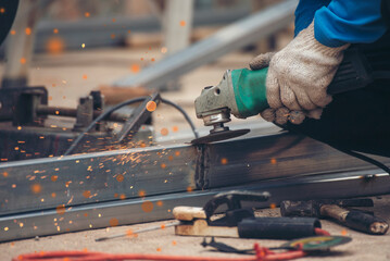 Construction Worker hands using Welding machinery iron metal sparking. Men hands wear protective...