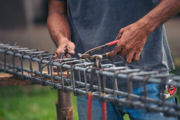 Construction Men hands bending cutting steel wire fences bar reinforcement of concrete work. Worker hands using pincer pliers iron wire. Outdoor Worker using wire bending pliers, construction work - obrazy, fototapety, plakaty