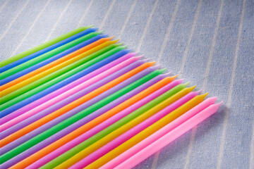 Colorful candle birthday candles on blue striped fabric background