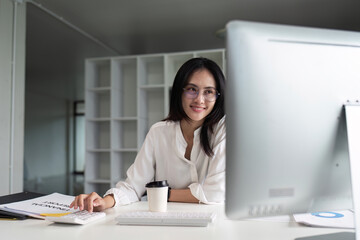 businesswoman accountant using calculator and computer for matching financial data saving in office room - obrazy, fototapety, plakaty