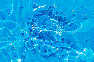 Defocus blurred transparent blue colored clear calm water surface texture with splashes reflection. Trendy abstract nature background. Water waves in sunlight with copy space. Blue watercolor shine.