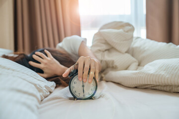 alarm clock and asian woman hand stop time in bed while sleeping, young adult female wake up late in the early morning. Relaxing , sleepy, daily routine and have a nice day concepts - obrazy, fototapety, plakaty