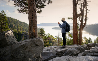 Woman taking videos using smartphone at Emerald Bay. South Lake Tahoe at sunrise. California.