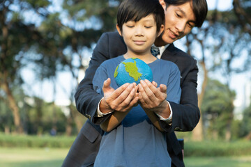 Asian boy and businessman holding planet Earth together as Earth day concept as corporate social...