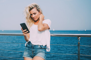 Charming female watching mobile in seafront