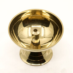 a symmetric golden oil diya lamp with a wick stand made of brass used for temple worship isolated in a white background