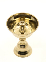 a symmetric golden oil diya lamp with a wick stand made of brass used for temple worship isolated in a white background