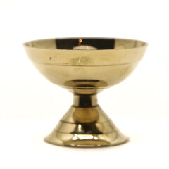 a symmetric golden oil diya lamp with a wick stand made of brass used for temple worship isolated in a white background