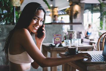 Ethnic woman in sportswear speaking on phone