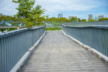 Asplalt running walk way in city public park with green tree forest and office building