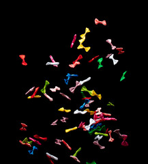 Bows flying in air. Many small ribbon in red, blue, pink, yellow throw explosion. Small Bow floating abstract black background isolated, high speed shutter freeze action