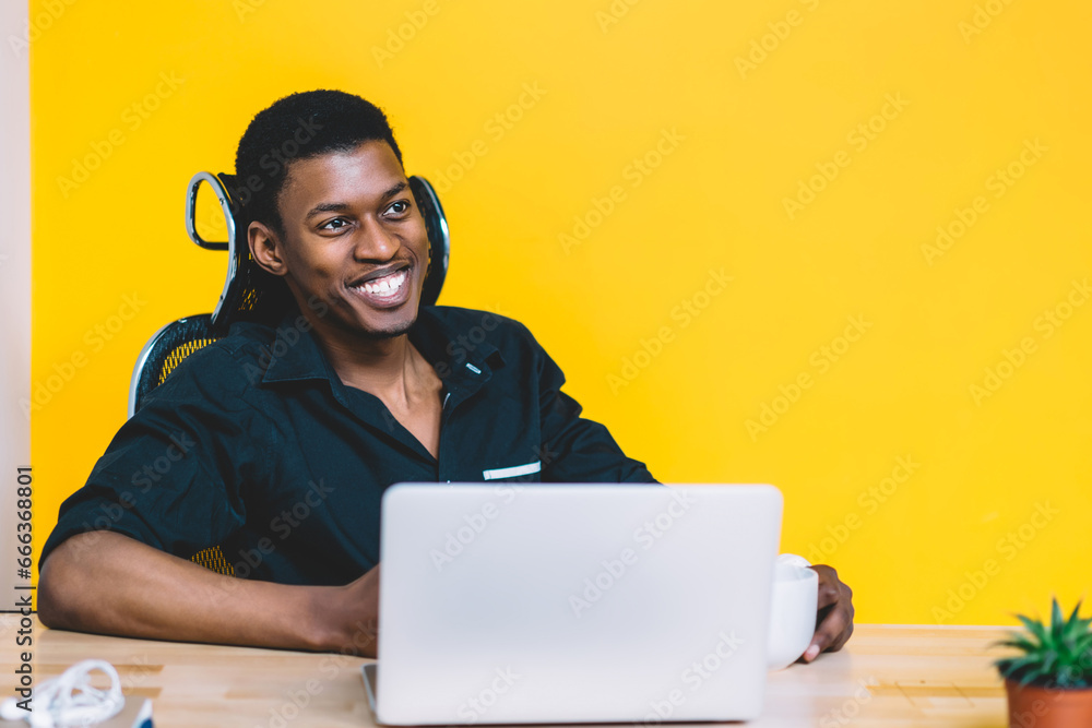 Poster happy african american software developer sitting at desktop with modern netbook
