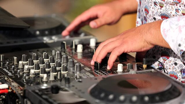 4K video with the hands of a DJ mixing outdoor in a garden party. Electronic music deejay concept video.